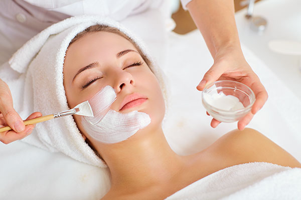 Close up of a woman receiving a facial with cream being applied to her face