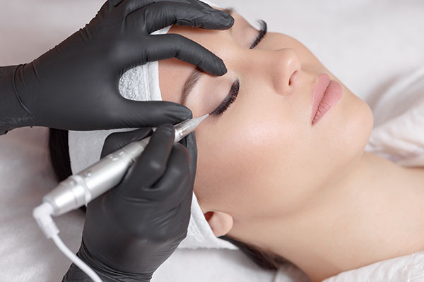 Technician applying permanent makeup to a woman's face